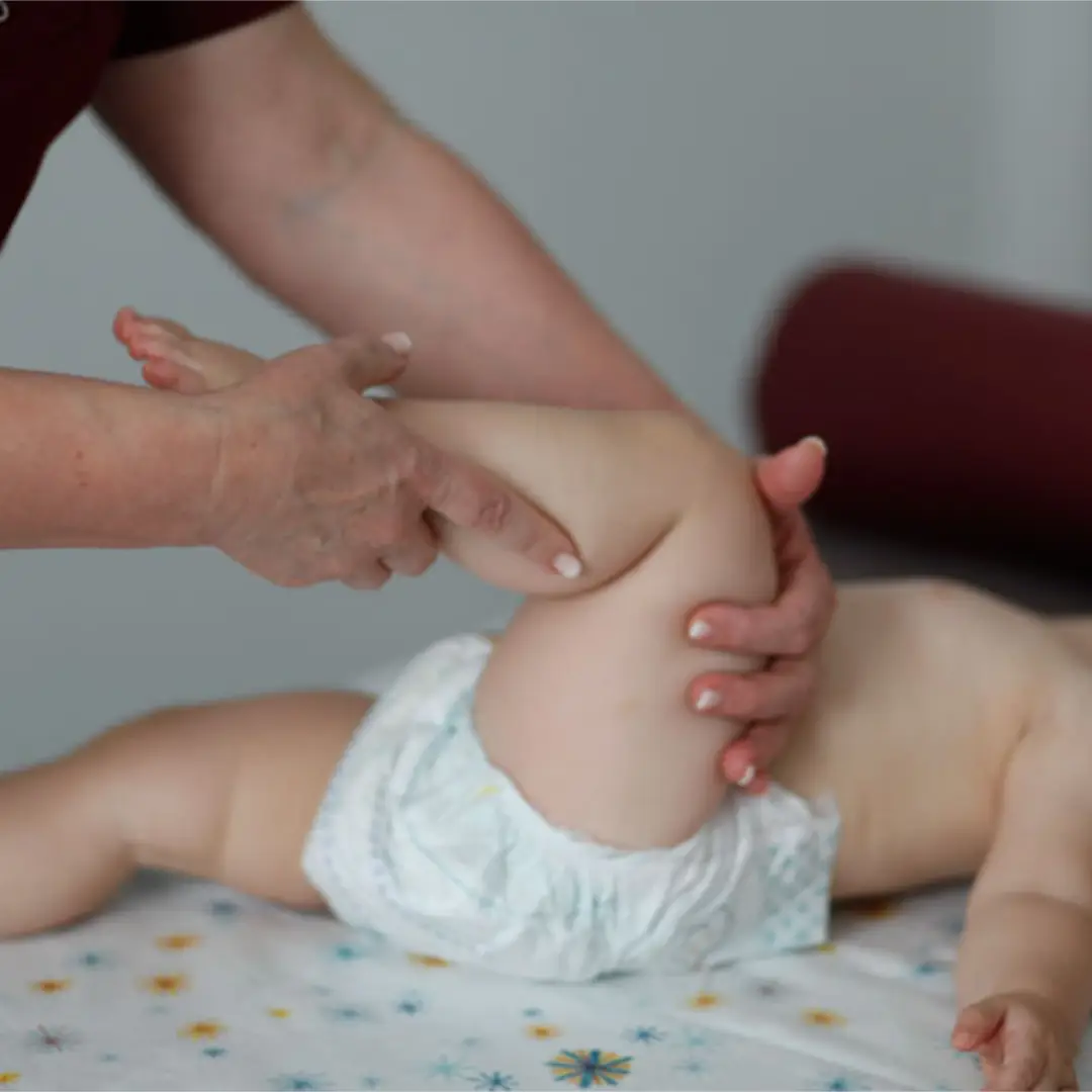 Kind liegt auf der Liege und macht eine Kniebeuge und bekommt eine Massage für Kinder